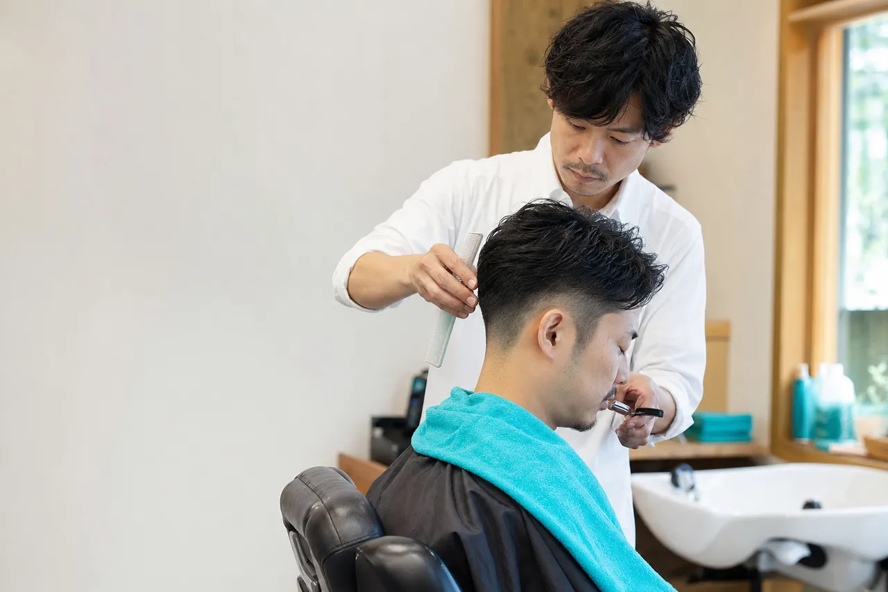 男性客のヒゲまわりをケアする理容師の手元