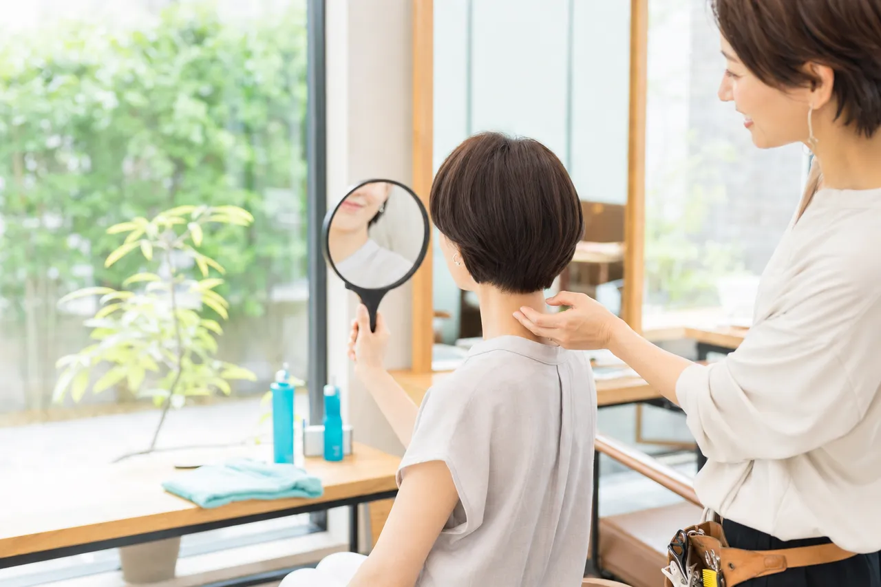 鏡でうなじを確認する女性客と美容師